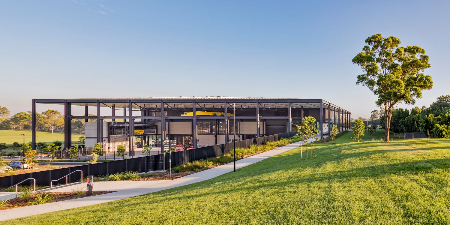 Modern steel-framed TAFE campus building with glass walls and a covered walkway beside a landscaped lawn under a clear blue sky.