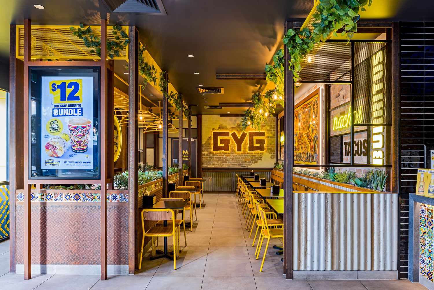 Fast-casual Mexican restaurant entrance with a GYG sign, yellow chairs, a $12 bundle poster and trailing green plants.