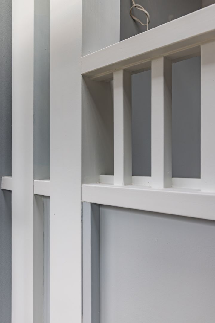 White timber battens and slatted balustrade detail against soft grey painted walls in a modern interior.