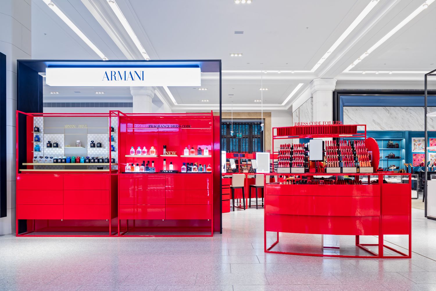 Armani beauty counter with red display units showcasing cosmetics and fragrances in a bright retail store.