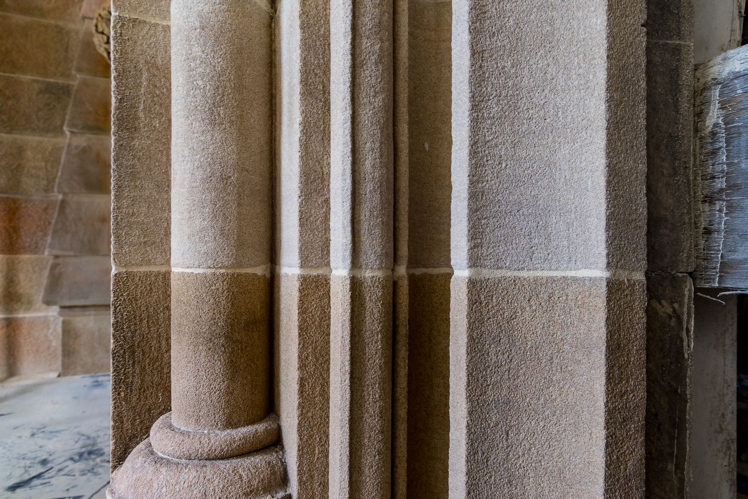 Close-up of sandstone clustered pillars with slim shafts and a rounded base in a Gothic stone interior.