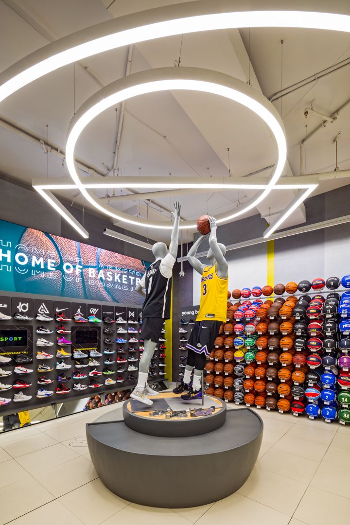Home of Basketball sports store with mannequins in Lakers jerseys, a wall of colorful basketballs, shoes and circular ceiling lights.