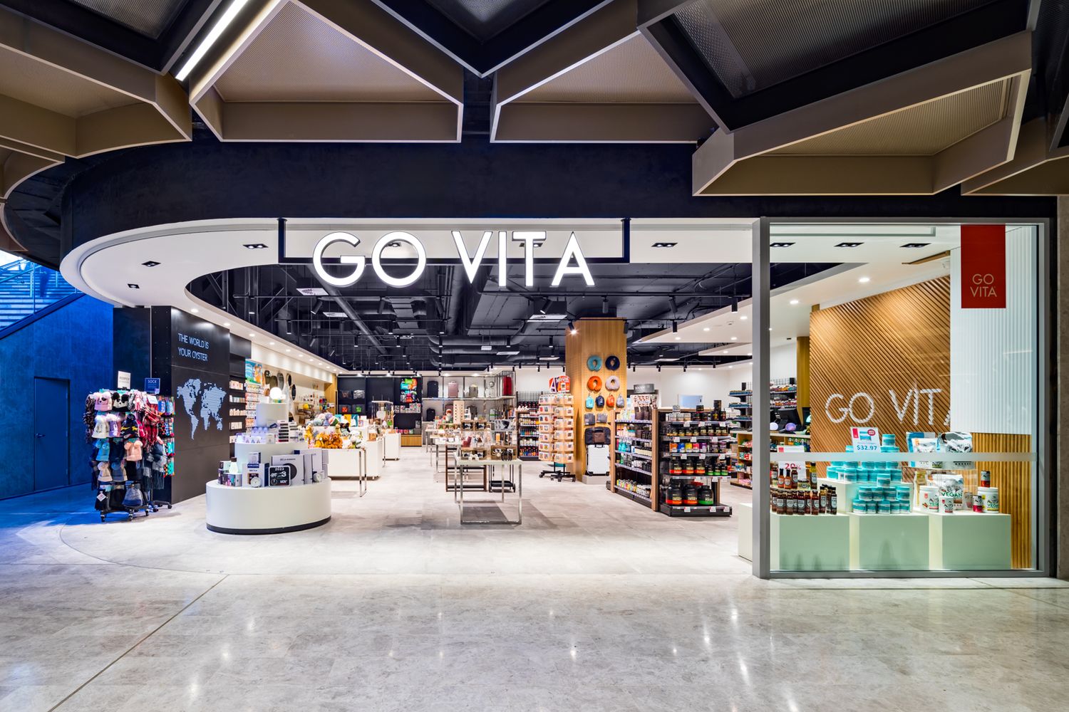 Go Vita health food store entrance in a modern shopping centre, showing shelves of wellness products beneath a stylish angular ceiling.