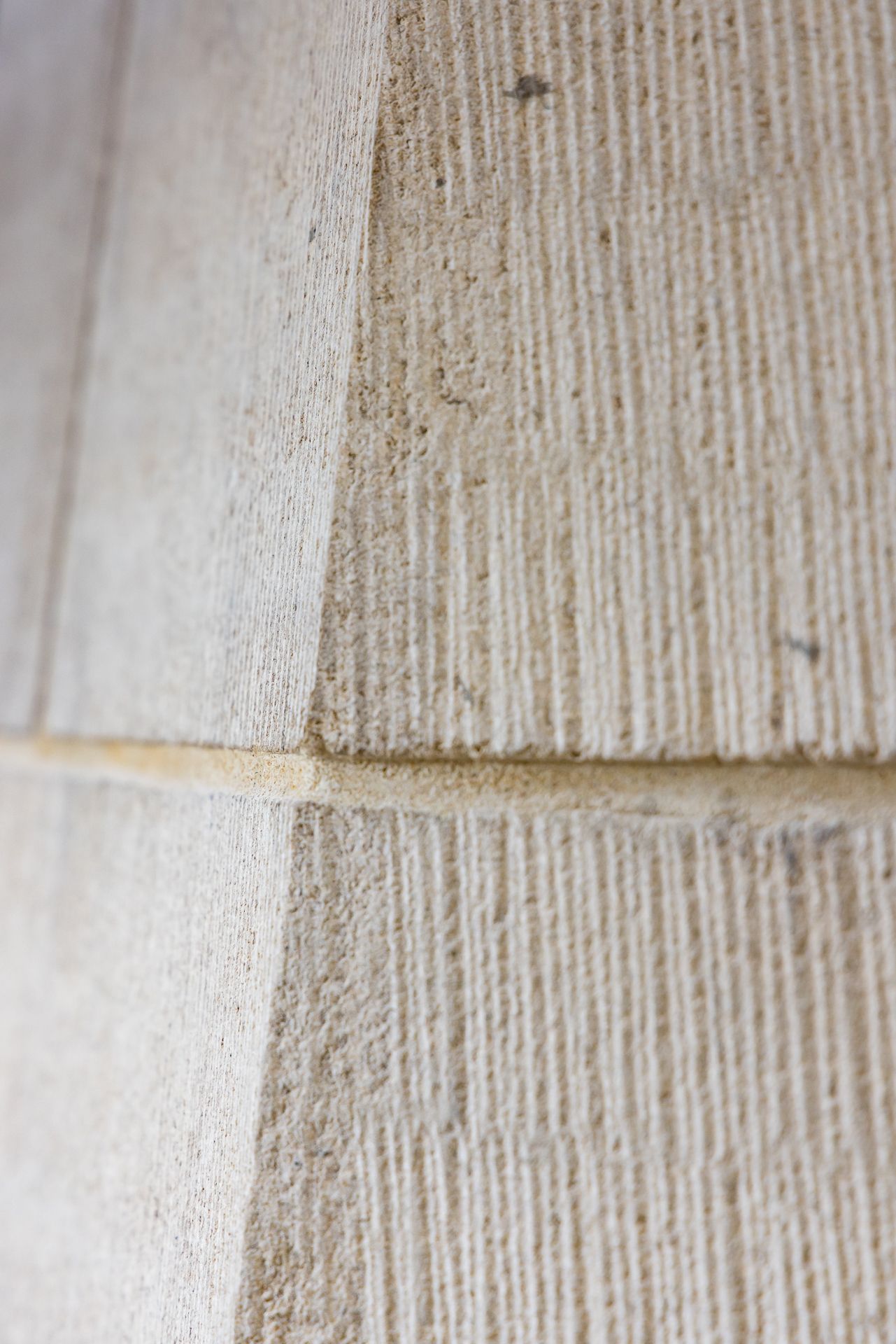 Macro view of hand-tooled sandstone showing fine parallel chisel lines and a crisp chamfered edge.