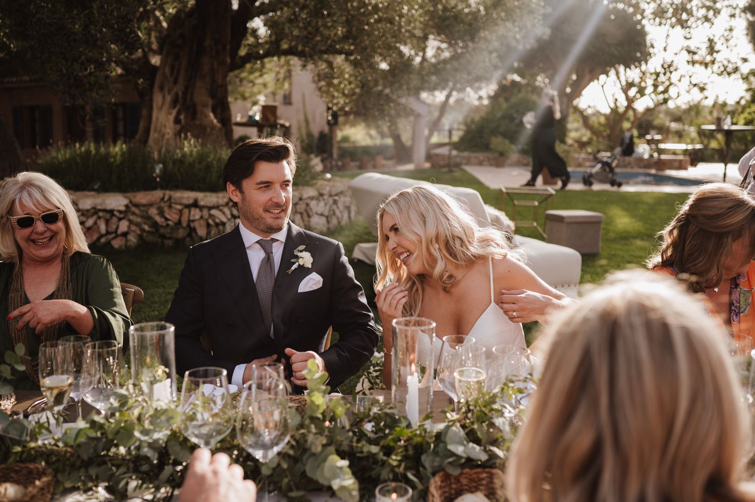 Bride and groom share a joyful moment at an elegant outdoor wedding reception dinner table.