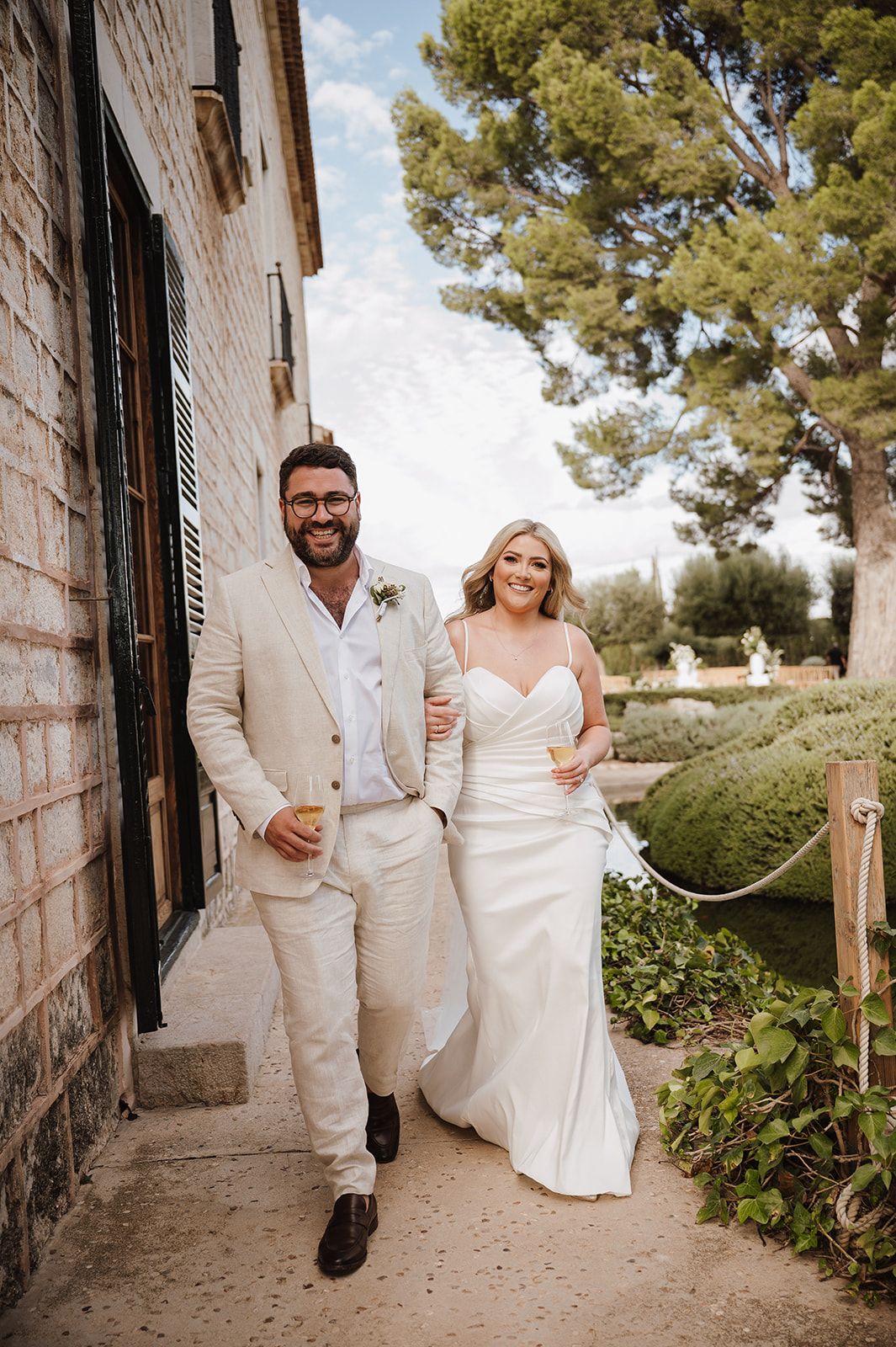 Smiling bride and groom walking together at an elegant outdoor wedding venue.