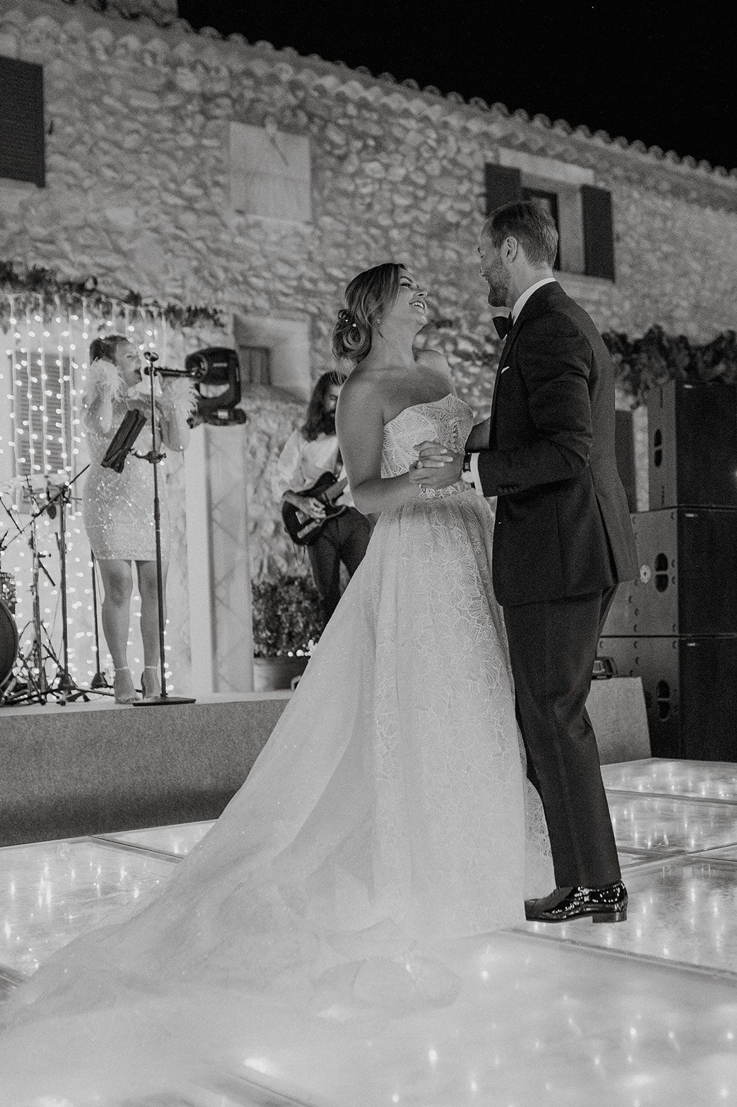 Bride and groom share their first dance on a lit dance floor at a rustic stone venue.