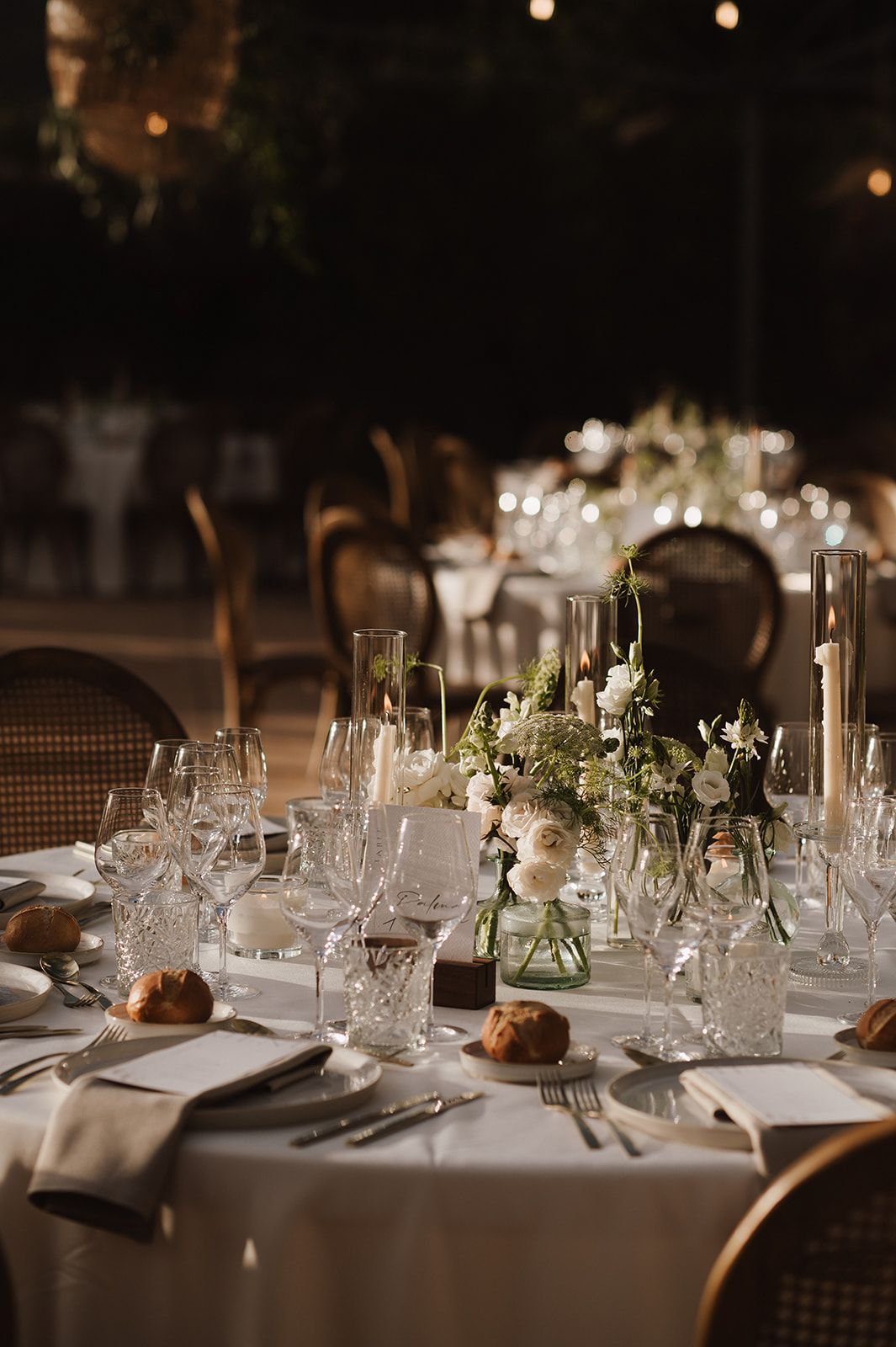 Elegant wedding reception table set with crystal glasses and white floral centerpieces.
