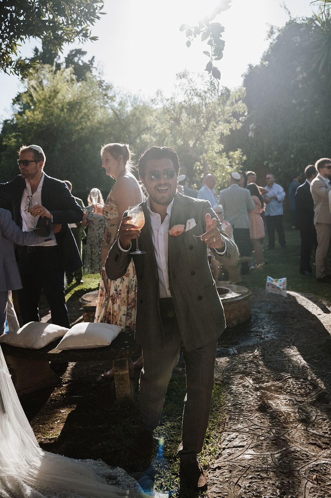 Smiling guest in suit poses at sunny outdoor wedding reception.