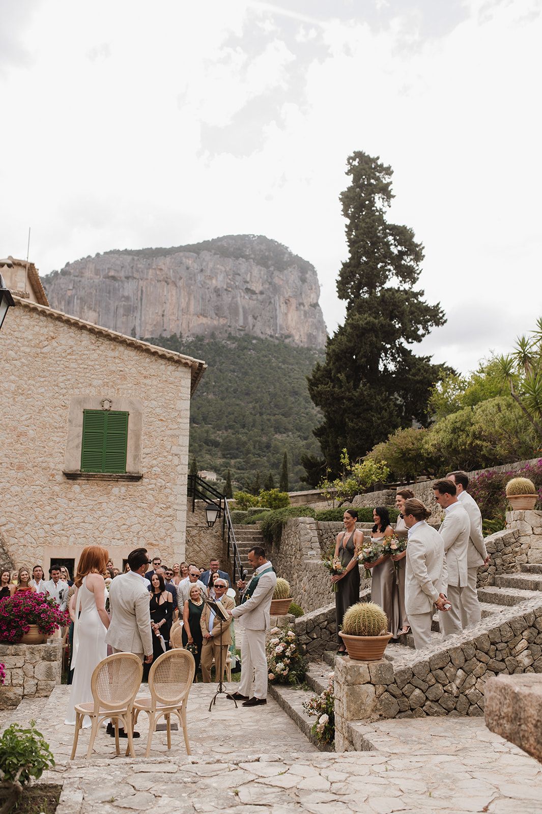 Outdoor wedding ceremony at a stone villa with dramatic rocky mountain backdrop in Mallorca Spain.