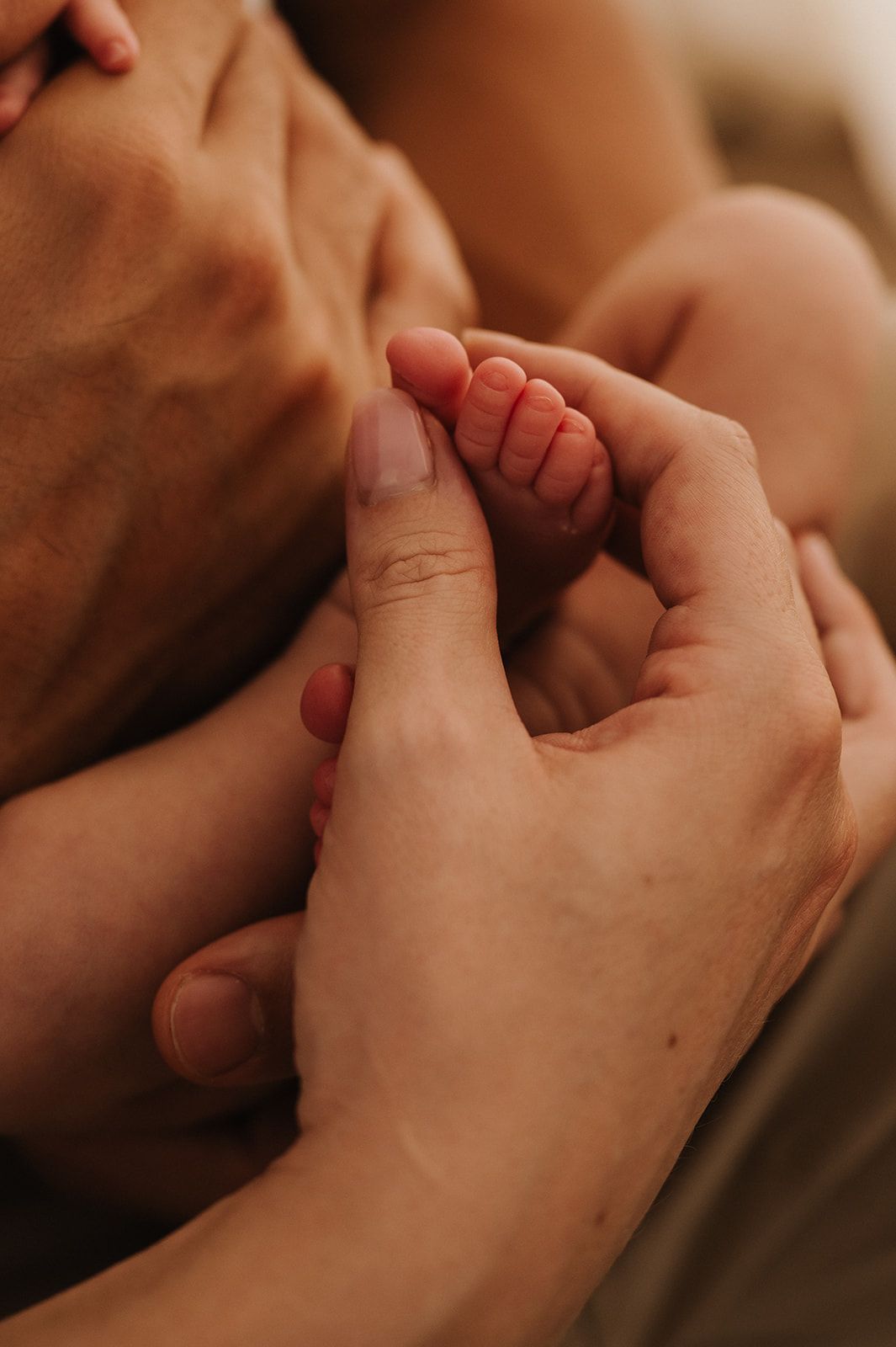 Newborn baby tiny hand grasping adult finger in tender close-up moment.