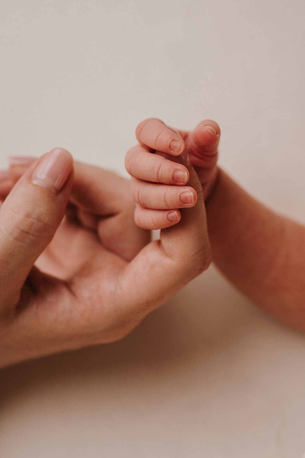 A tender close-up of a newborn baby grasping an adult's finger, symbolizing love and new parenthood.