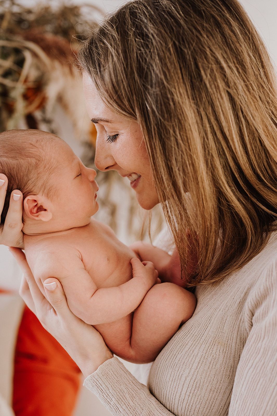 Mother tenderly holds her newborn baby close, touching noses in an intimate bonding moment.