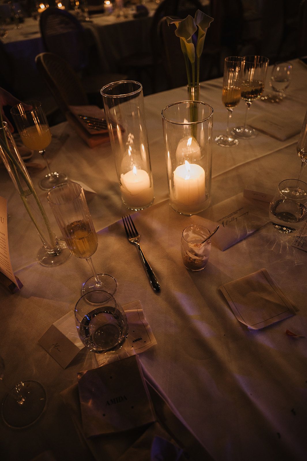 Romantic candlelit wedding reception table with glowing candles, crystal glasses, and elegant place settings.