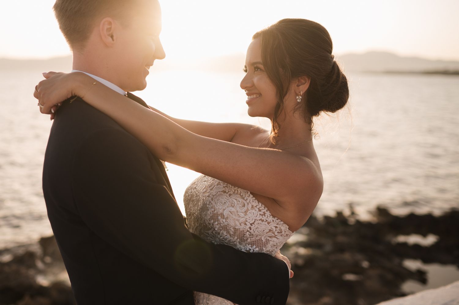 Bride smiling at groom during golden hour portrait session by the ocean at their wedding.