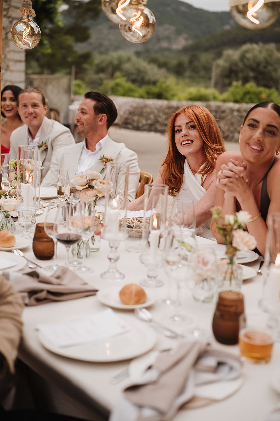 Happy wedding guests smiling and laughing at an elegant outdoor reception dinner table.
