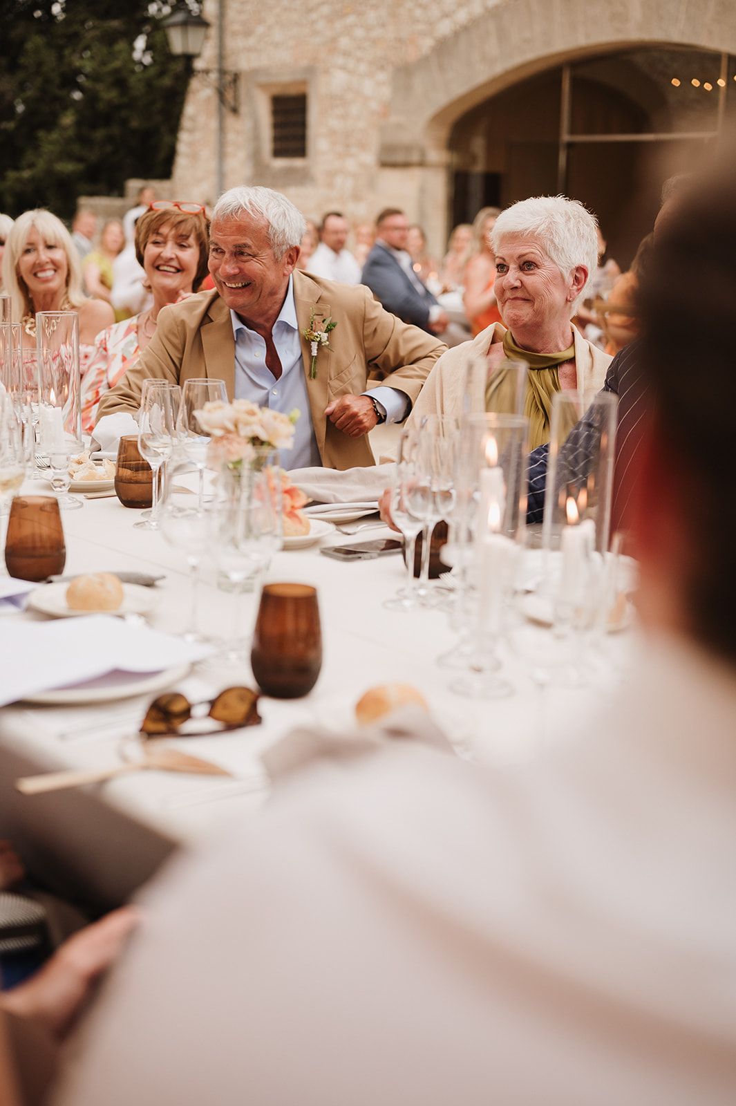 Elderly wedding guests laughing and enjoying dinner at an elegant outdoor reception table.