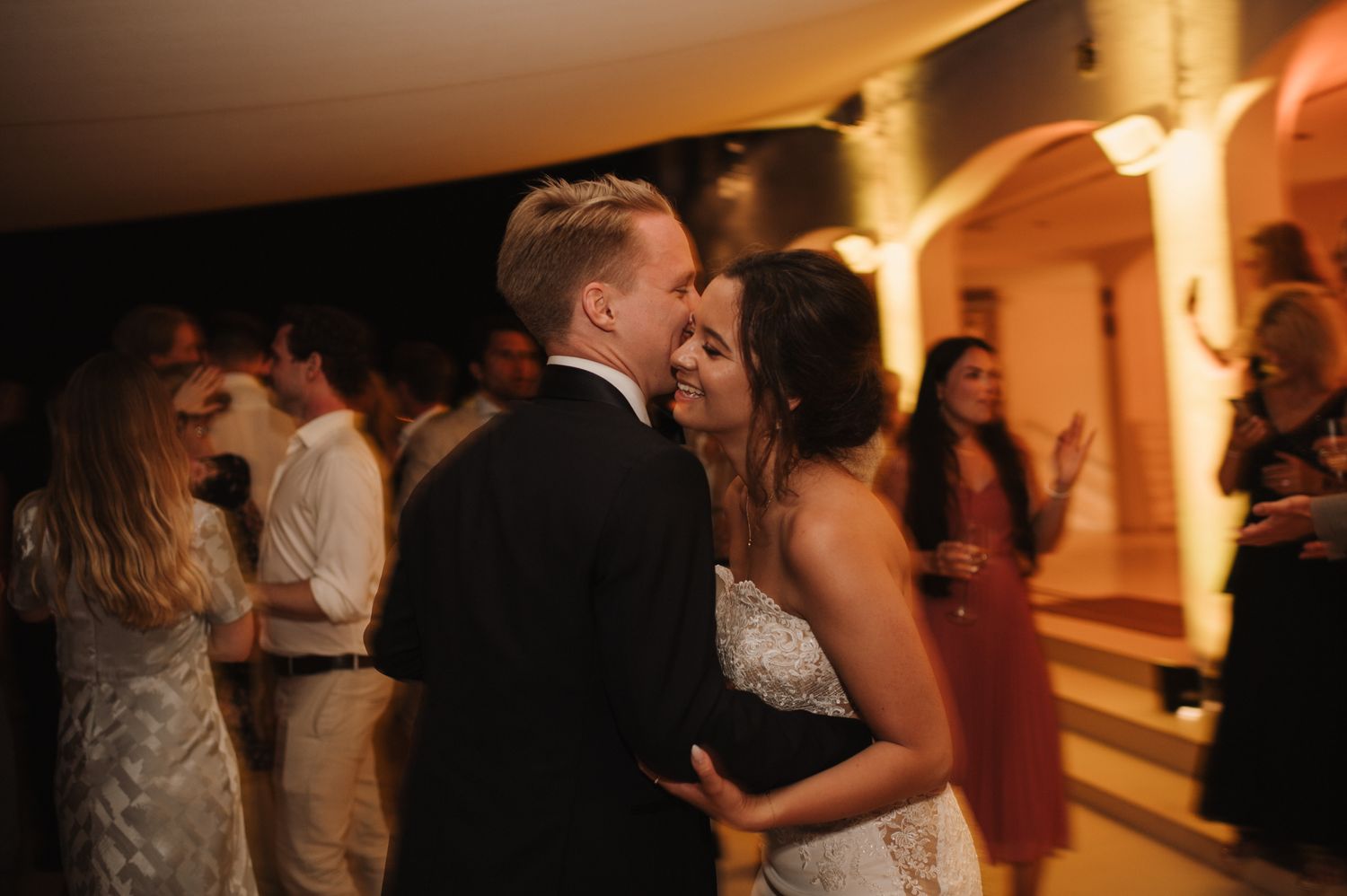 Bride and groom share first dance embracing at evening wedding reception celebration.