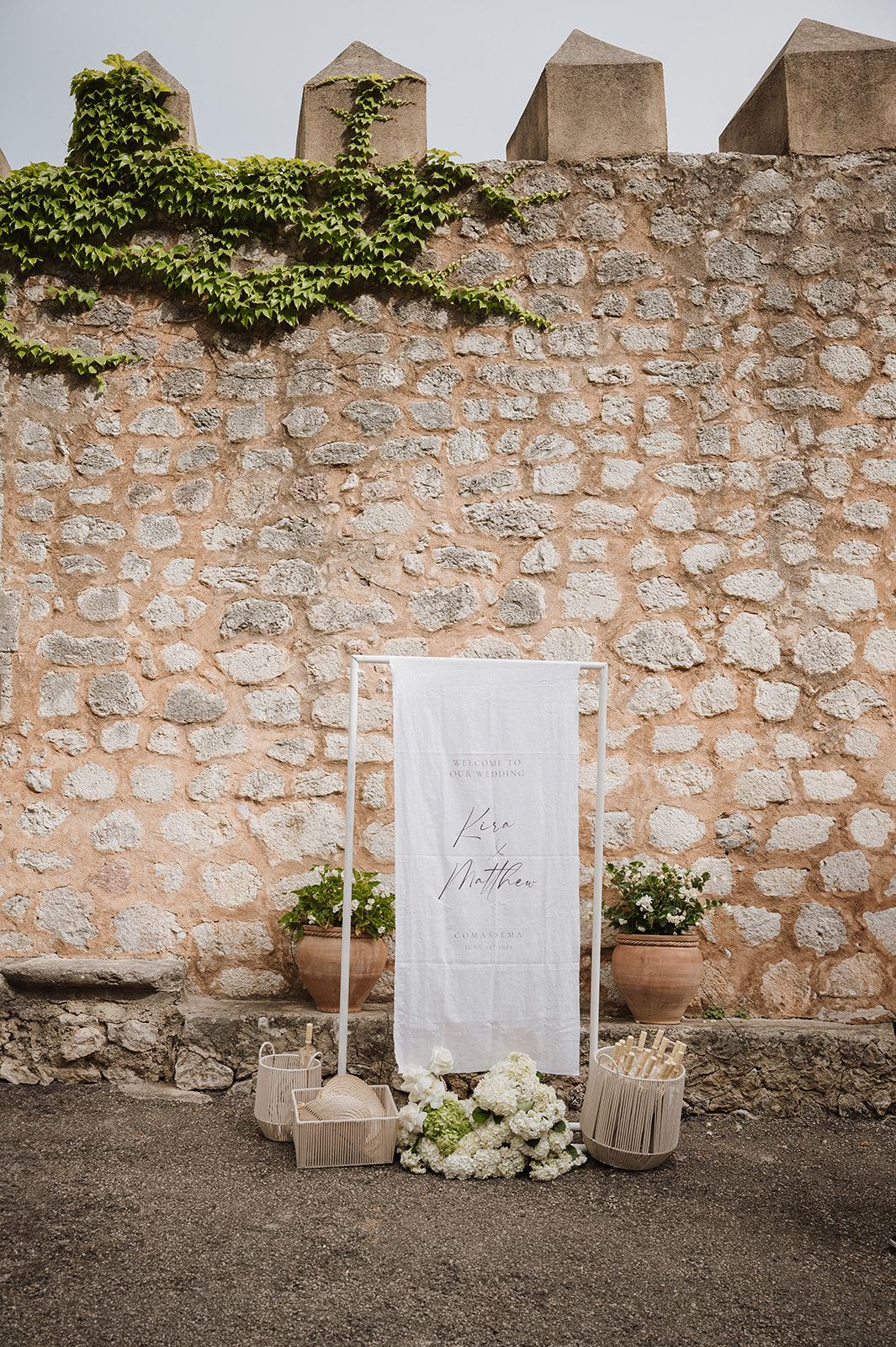 Elegant wedding welcome sign for Kara and Matthias displayed against rustic stone wall.