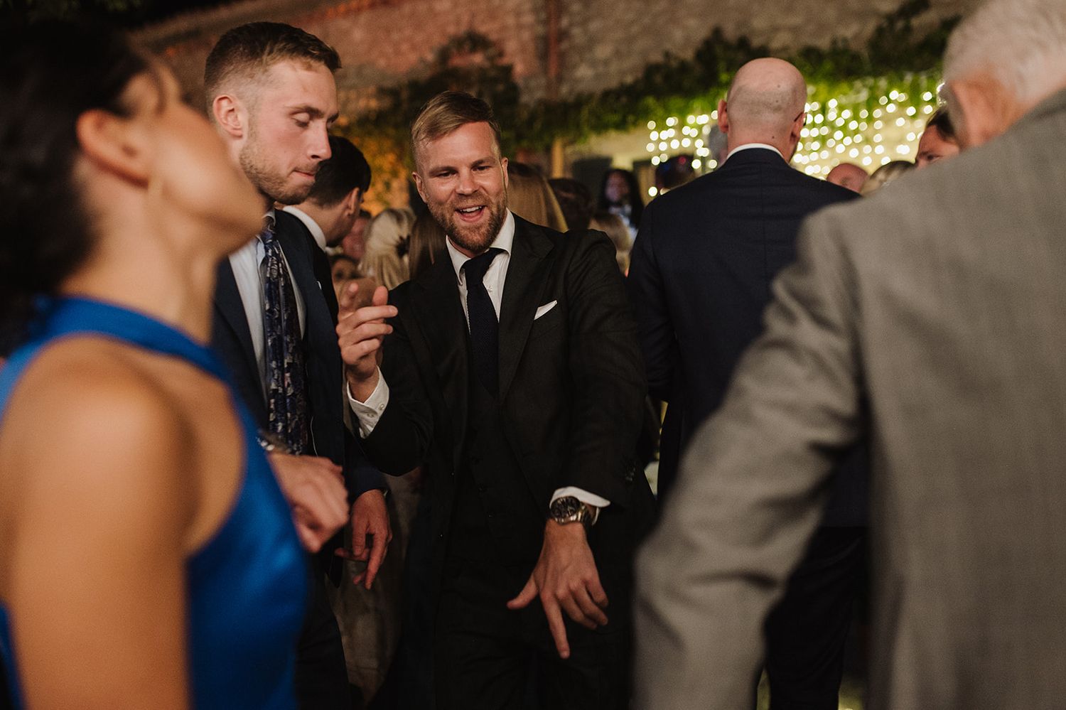 Guests in formal attire enjoy lively conversation on the wedding reception dance floor.