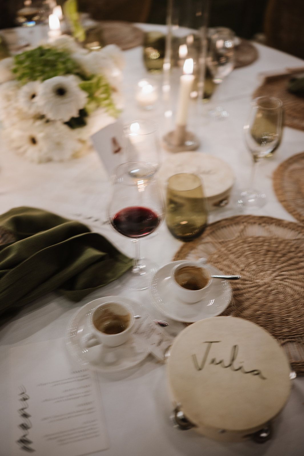 Elegant wedding table setting with candles, white flowers, wine glass, and personalized place card reading Julia.