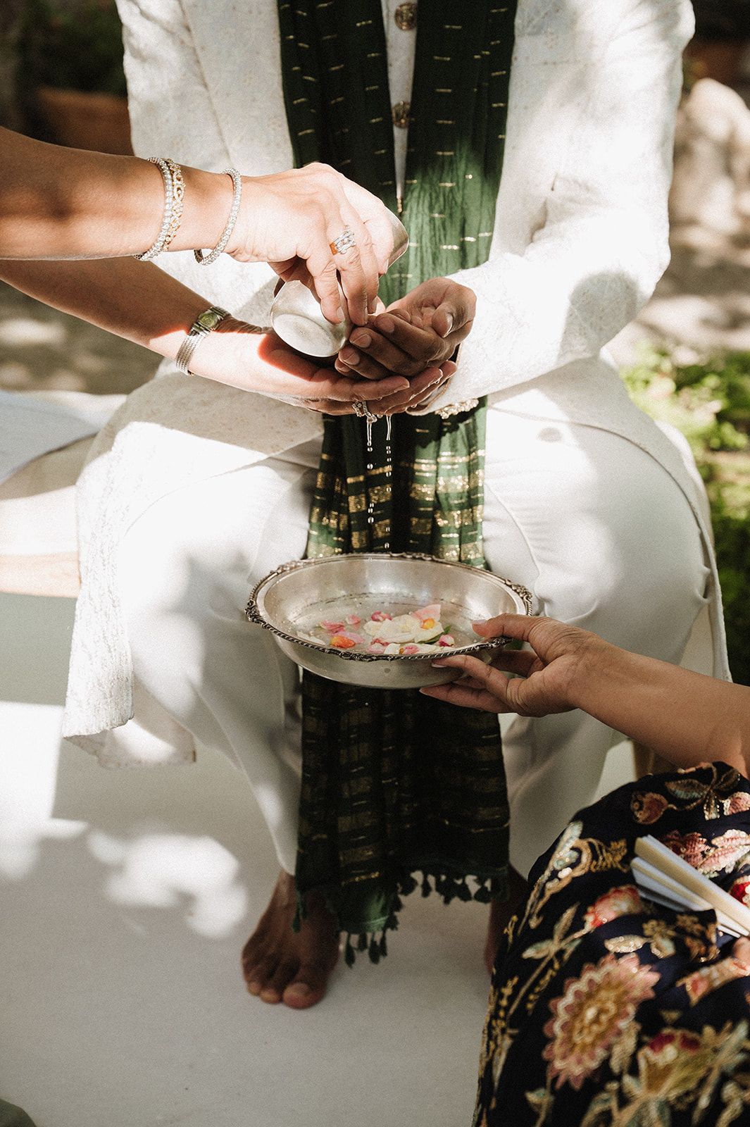 Hindu wedding ritual with water blessing ceremony over joined hands.