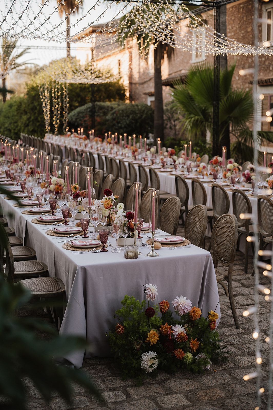 Elegant outdoor wedding reception with long tables, candles, and string lights.