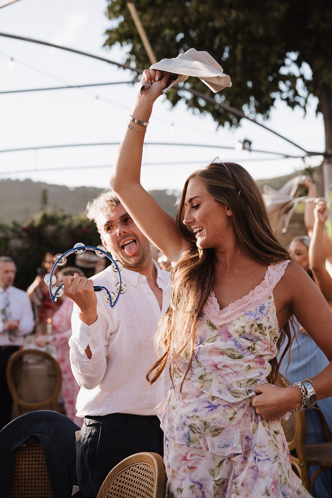 Joyful wedding guests dancing and celebrating outdoors at a summer reception.