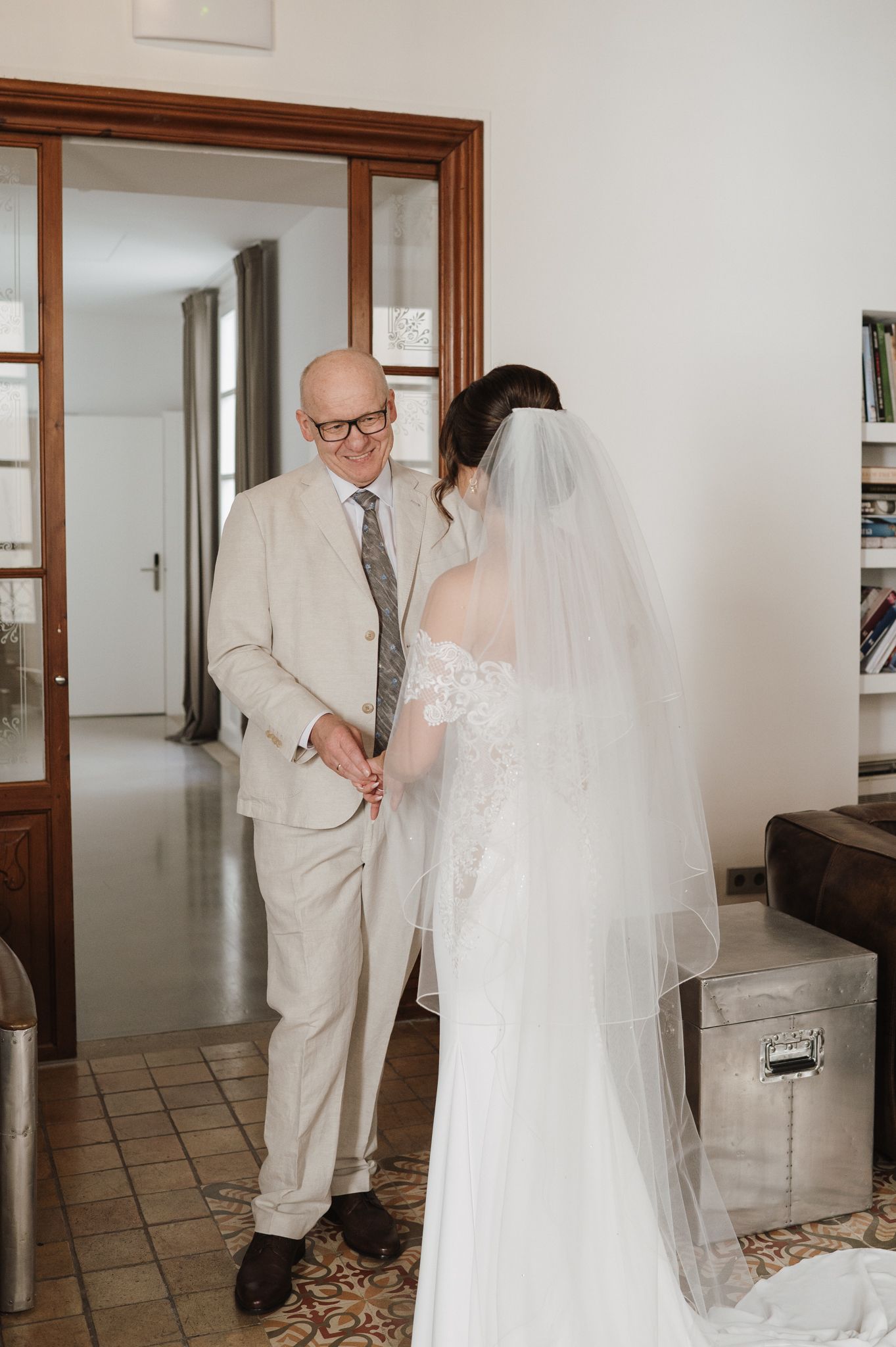 Bride in lace wedding gown and veil shares a tender moment with her father before the ceremony.