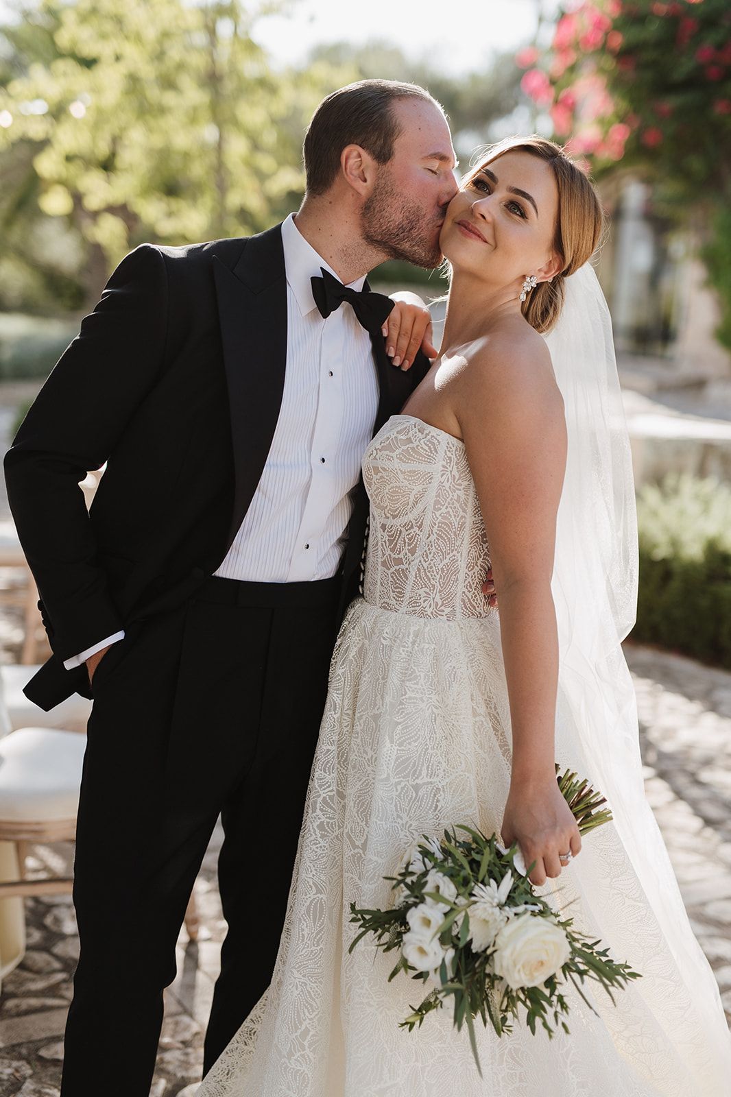 Bride and groom share a tender kiss during their outdoor wedding portrait session.
