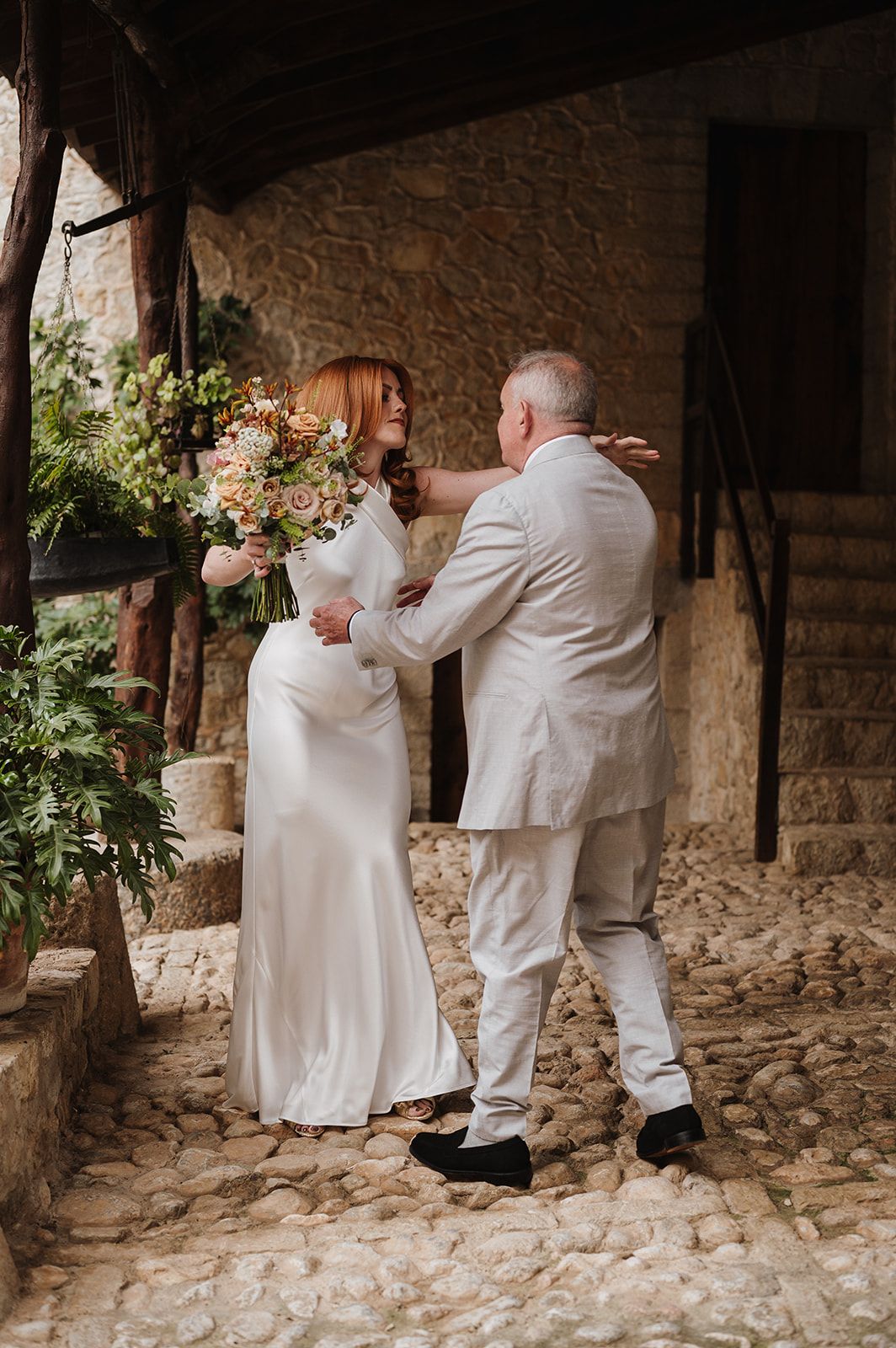 Bride and groom sharing a tender first look moment on a rustic cobblestone wedding venue.