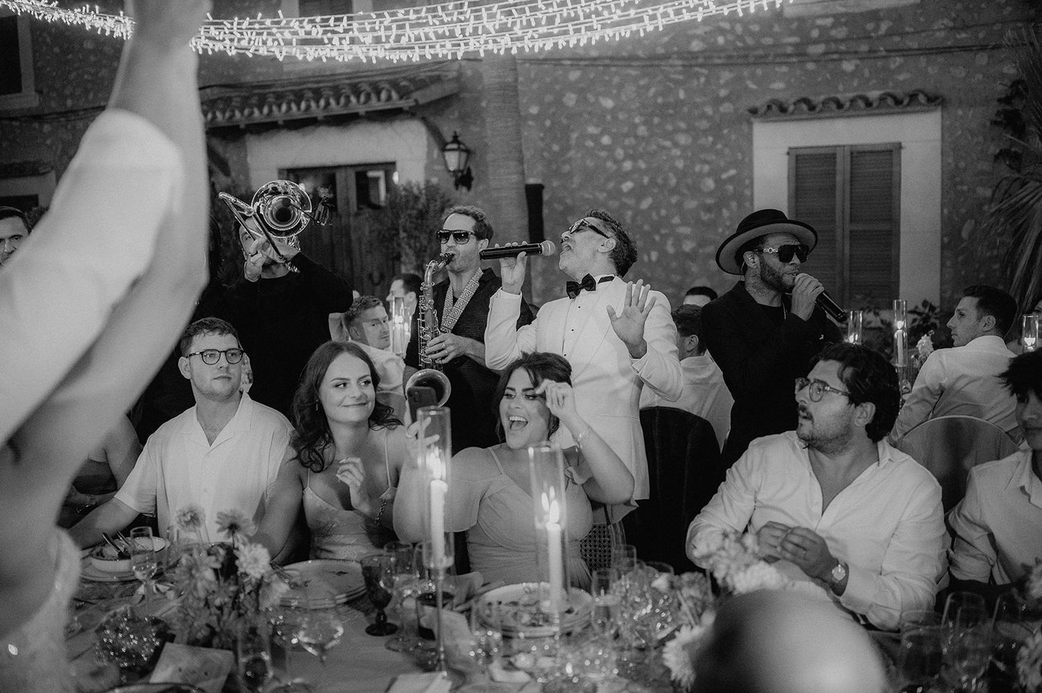 Live band performing at outdoor wedding reception while guests celebrate under string lights.