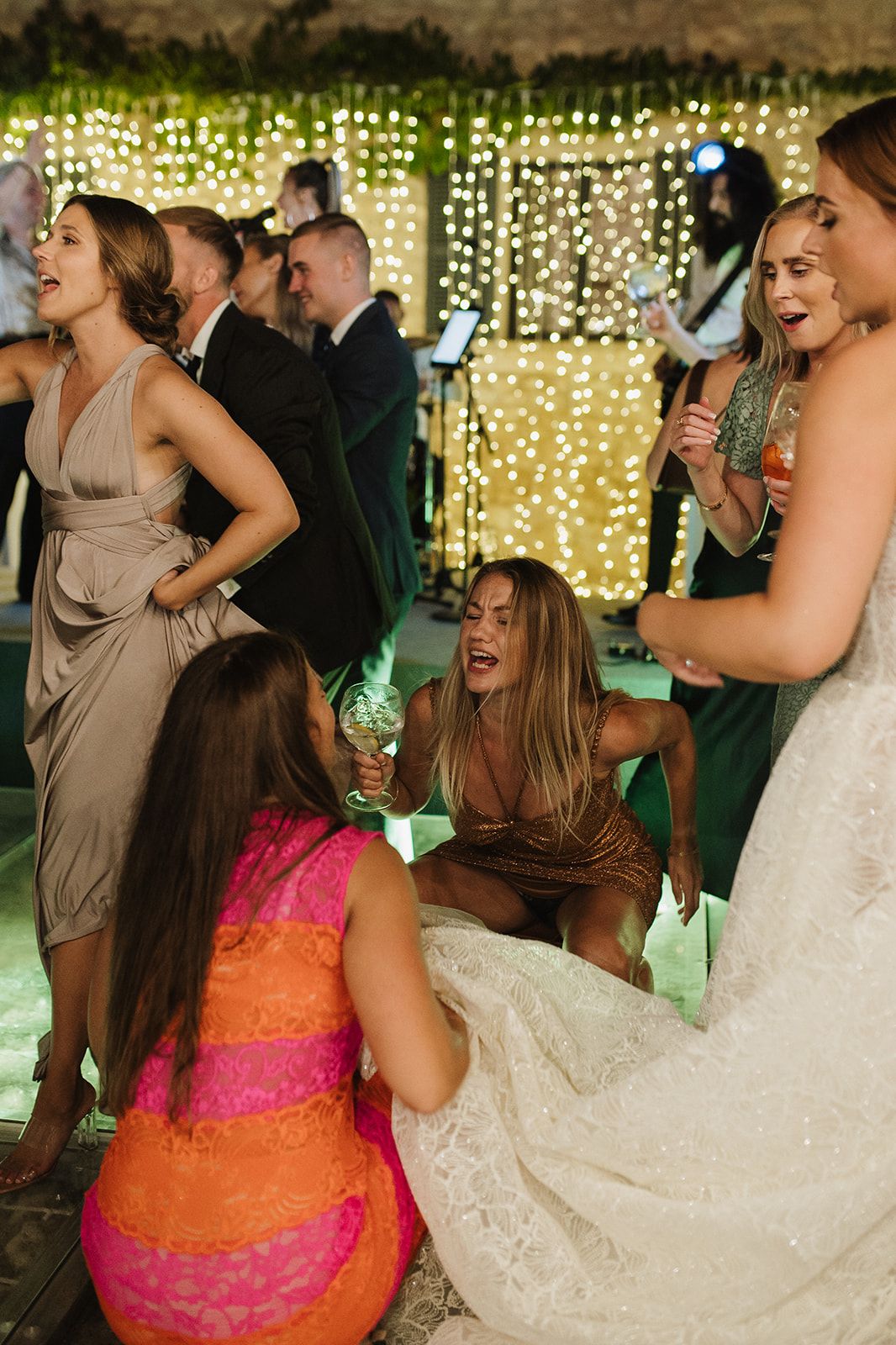 Bride and bridesmaids celebrate joyfully on the dance floor at the wedding reception.