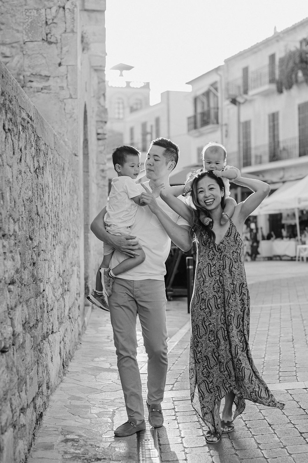 Black and white photo of a family of four walking through a historic European town square.