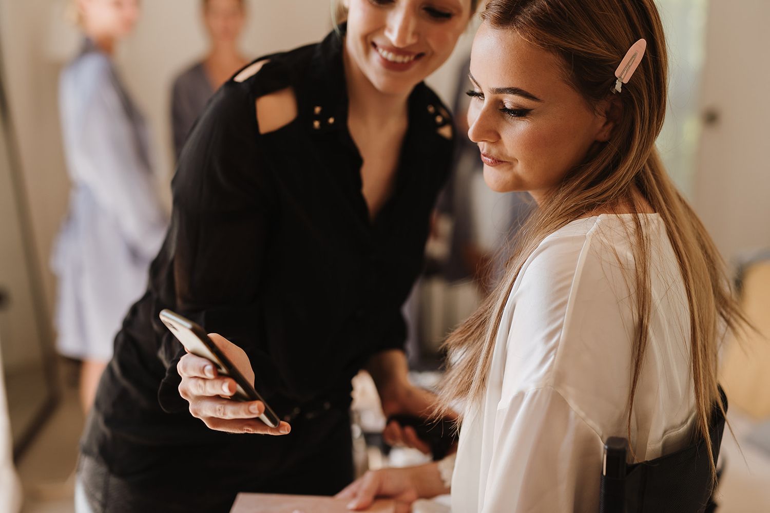 Wedding planner shows bride inspiration on phone during bridal preparations before the ceremony.