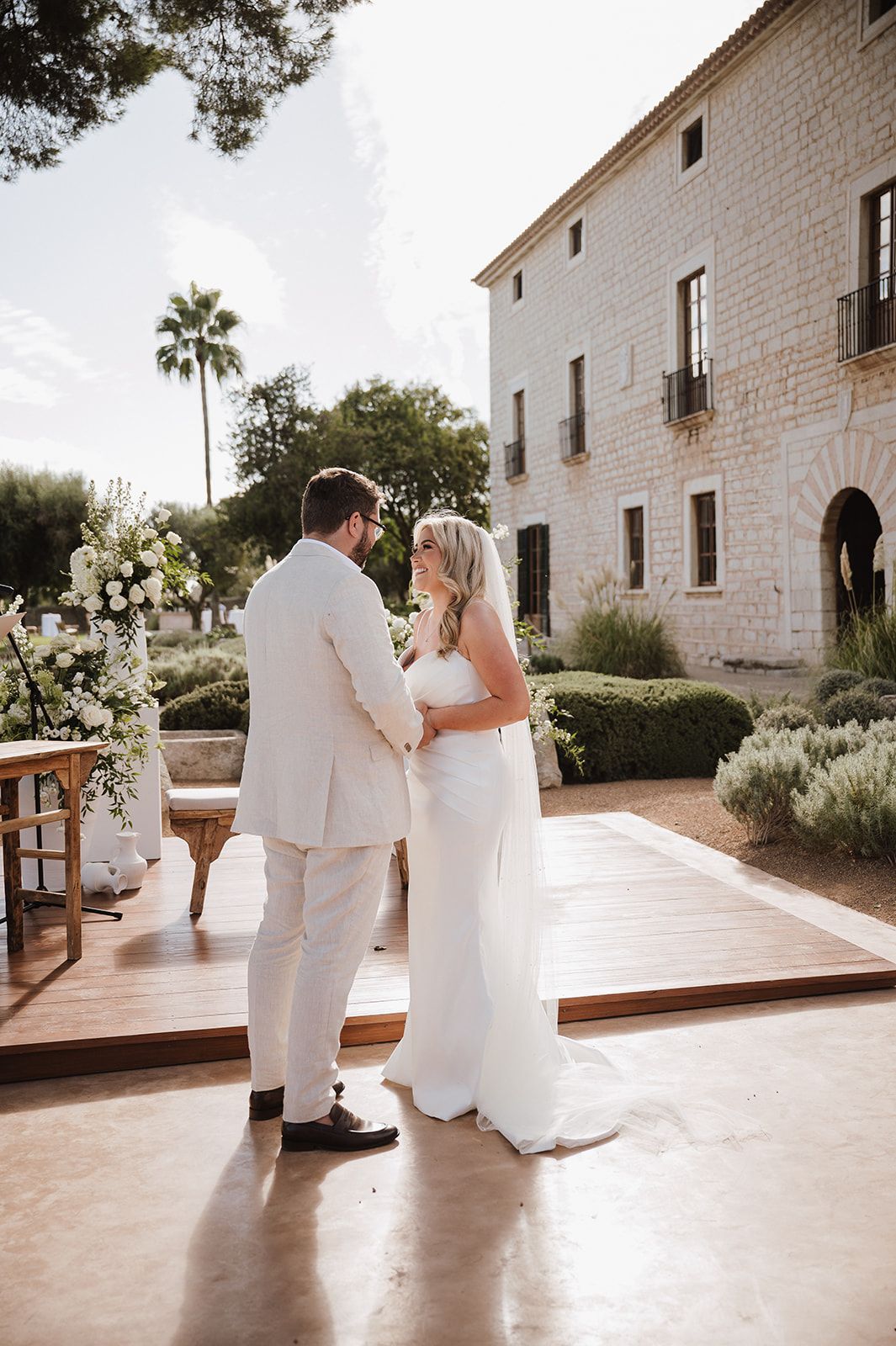 Bride and groom share an intimate moment during outdoor wedding ceremony at elegant stone villa venue.