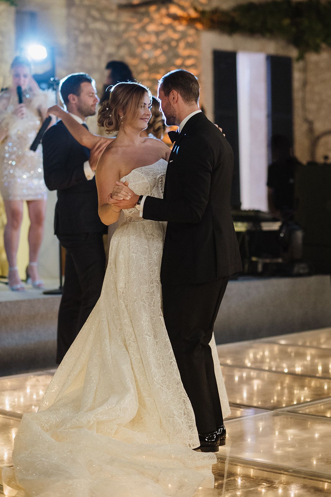 Bride and groom share their first dance on a candlelit dance floor at wedding reception.