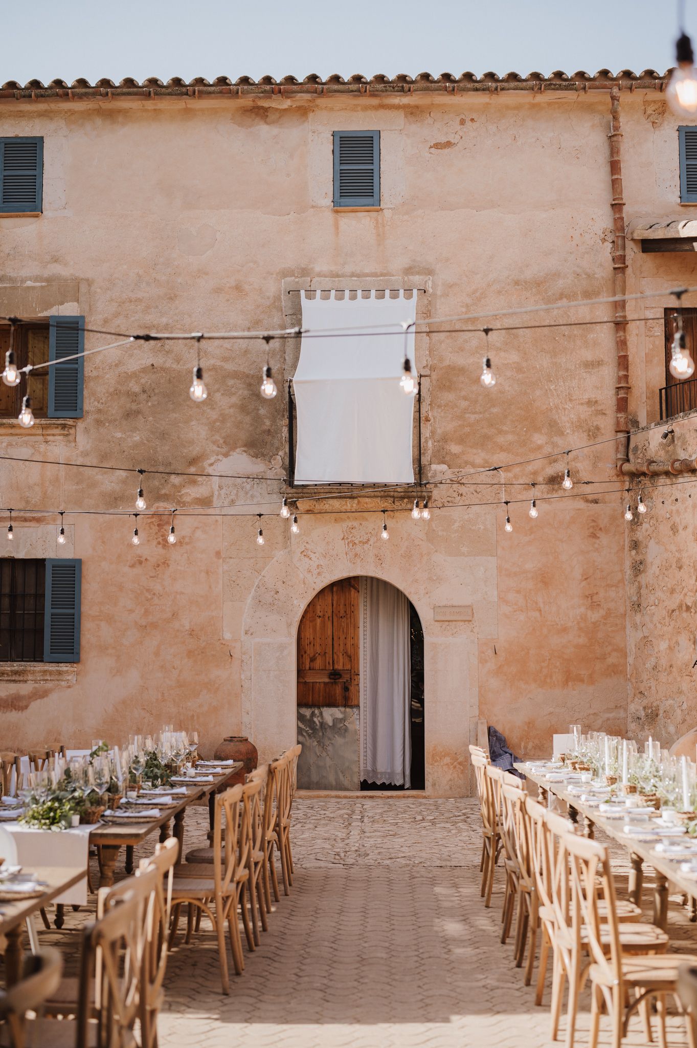 Rustic outdoor wedding reception tables set under string lights at a Mediterranean venue.