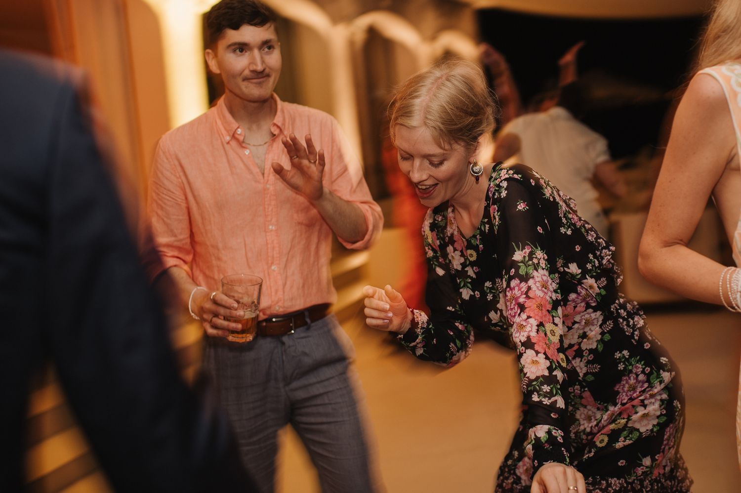 Wedding guests dance energetically at a lively indoor wedding reception celebration.