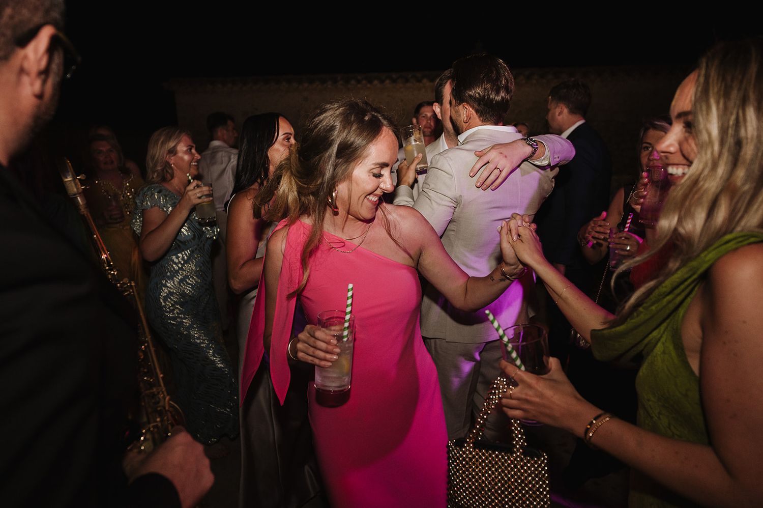 Guests in colorful outfits dancing and celebrating at an outdoor wedding party.