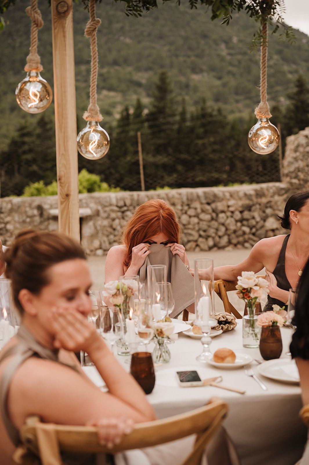 Wedding guest hiding behind menu at elegantly decorated outdoor dinner reception table.