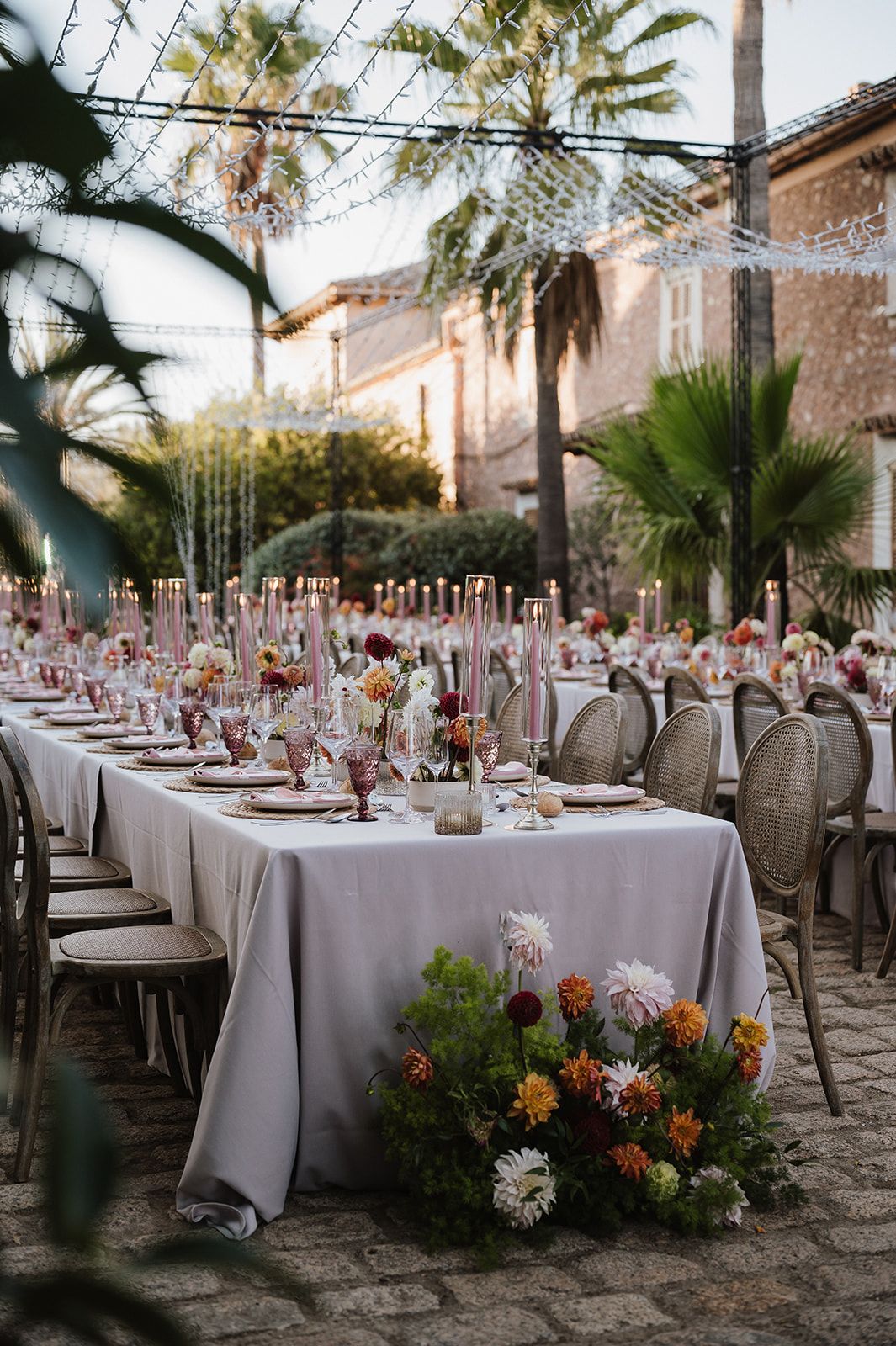 Elegant outdoor reception table with tall candles and colorful florals.