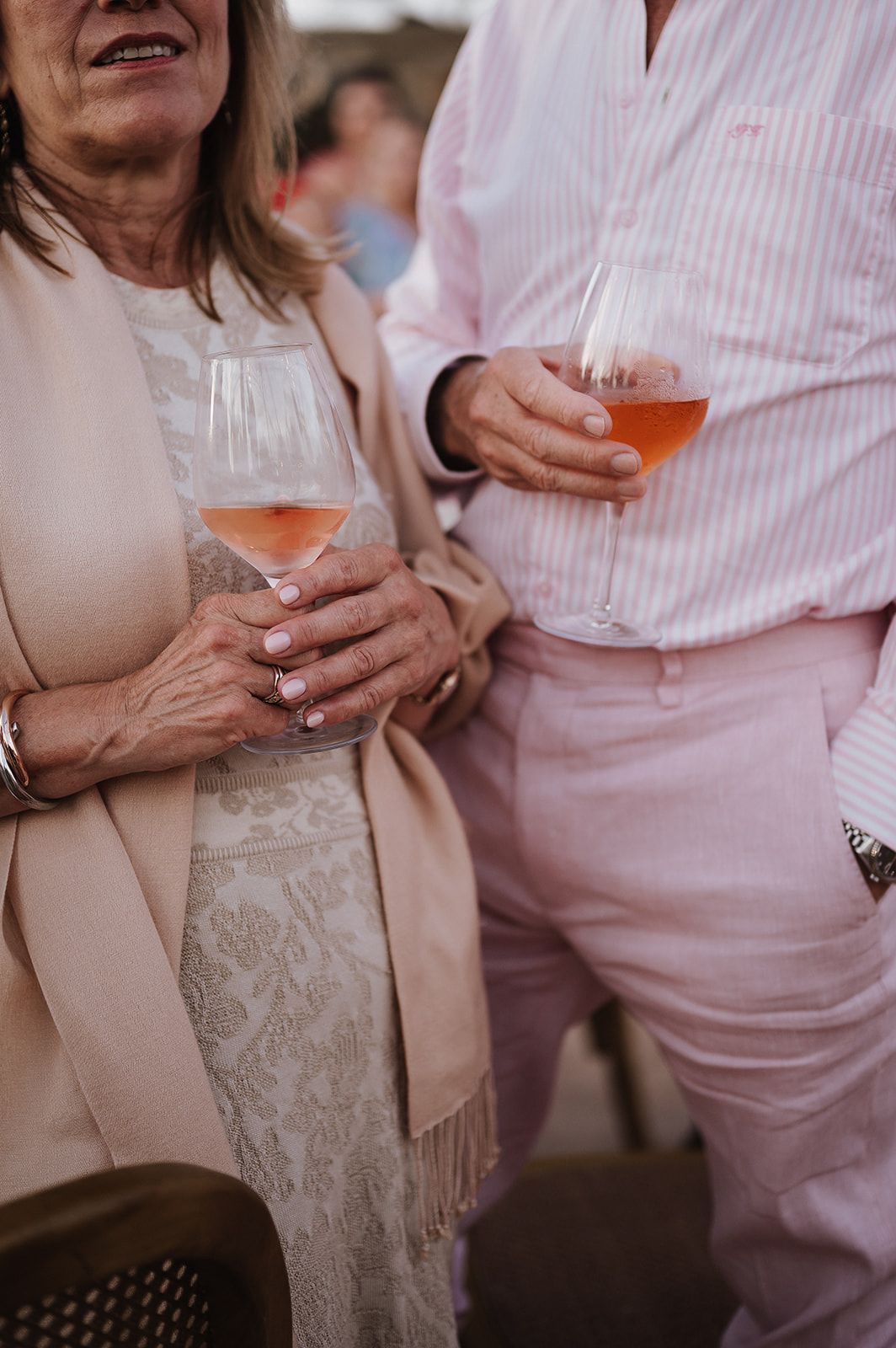 Wedding guests holding glasses of rose wine at an outdoor celebration event.
