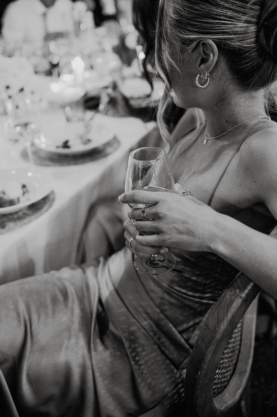 Black and white photo of bridesmaid holding champagne flute at elegant wedding reception table.