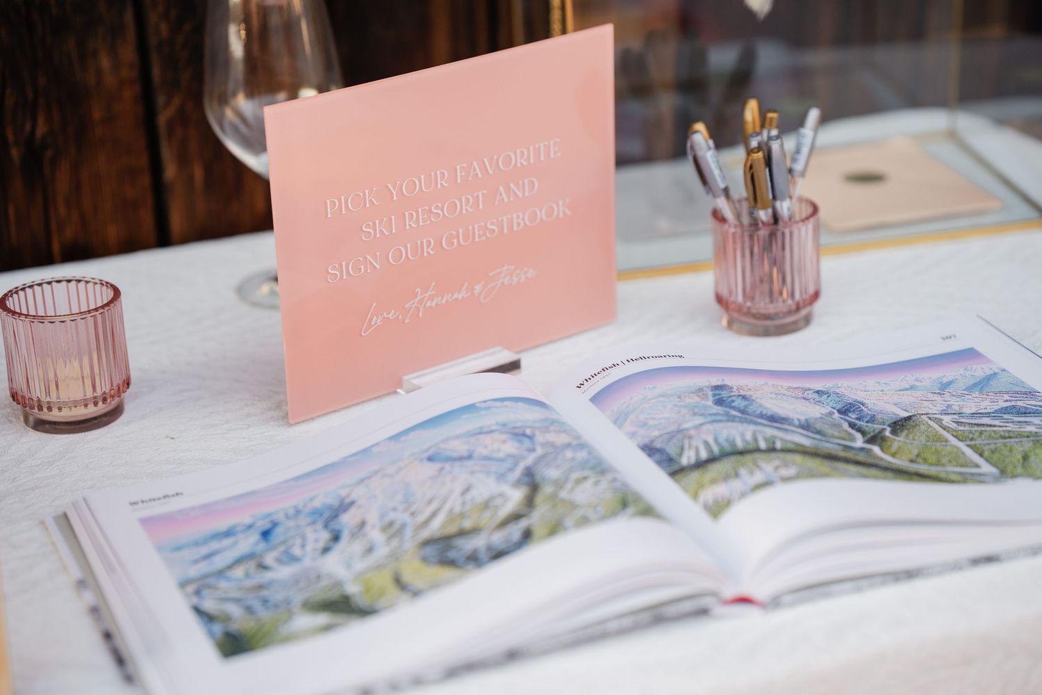 Wedding guest book table with watercolor mountain book and pink sign at elegant reception.