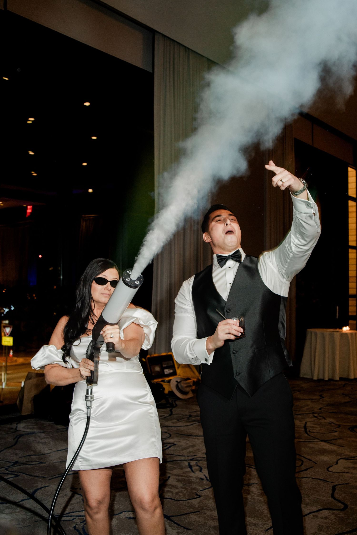 Bride and groom using CO2 cannon at lively wedding reception dance party.