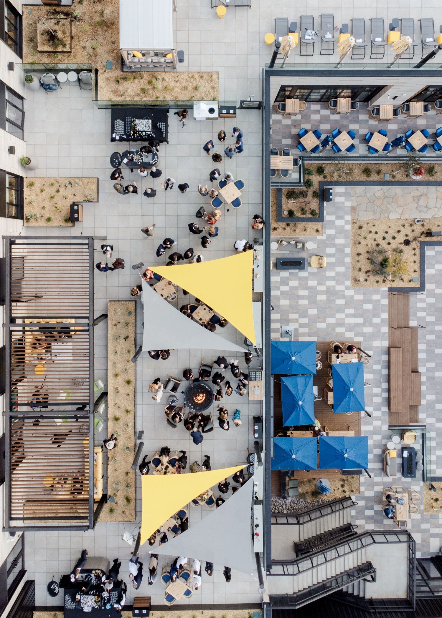 Aerial overhead view of outdoor wedding reception venue with yellow shade sails and guests mingling.