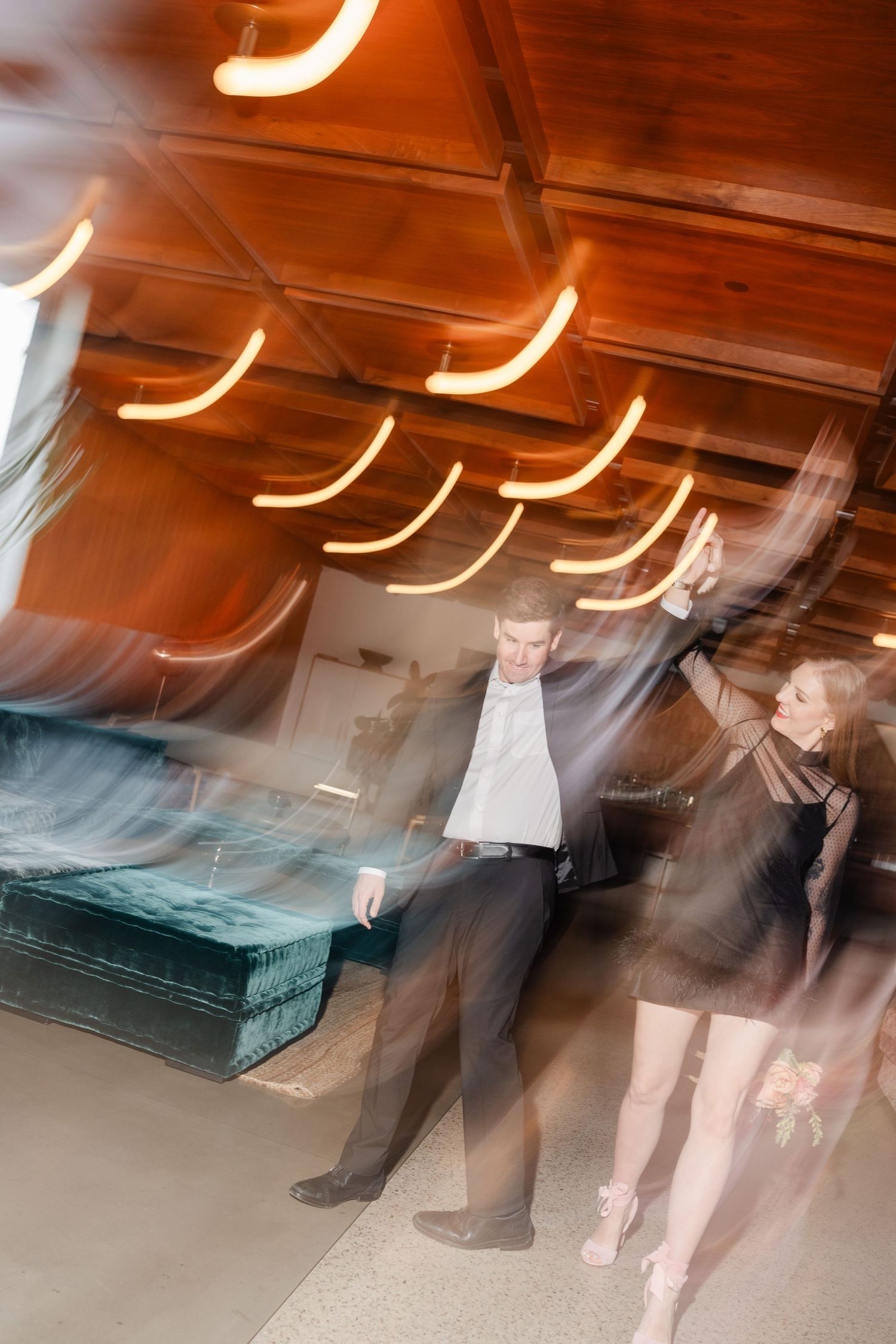 Couple dancing with motion blur and warm bokeh lights at an elegant indoor wedding reception.