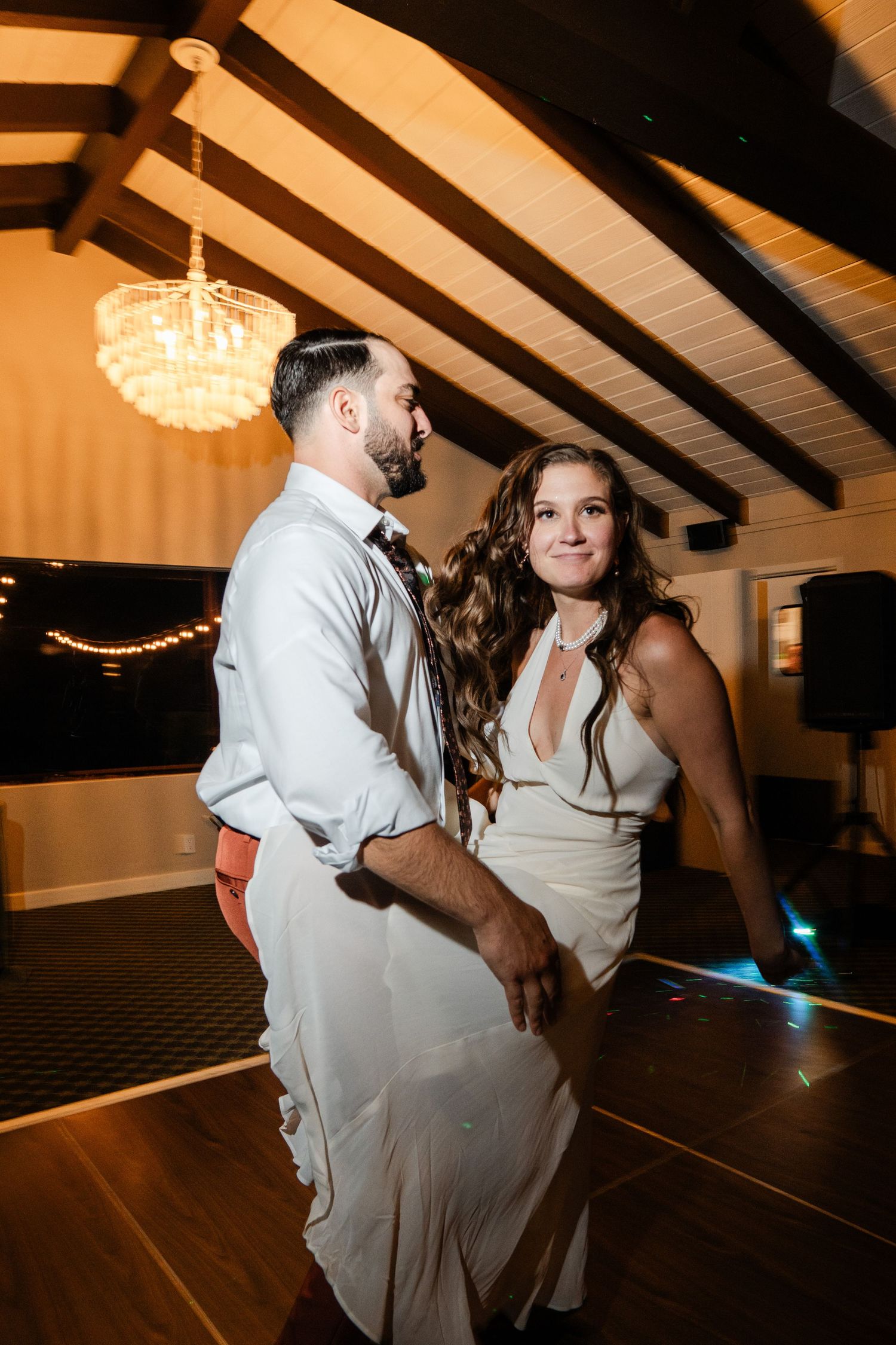 Bride and groom sharing a romantic slow dance under a chandelier at their wedding reception.