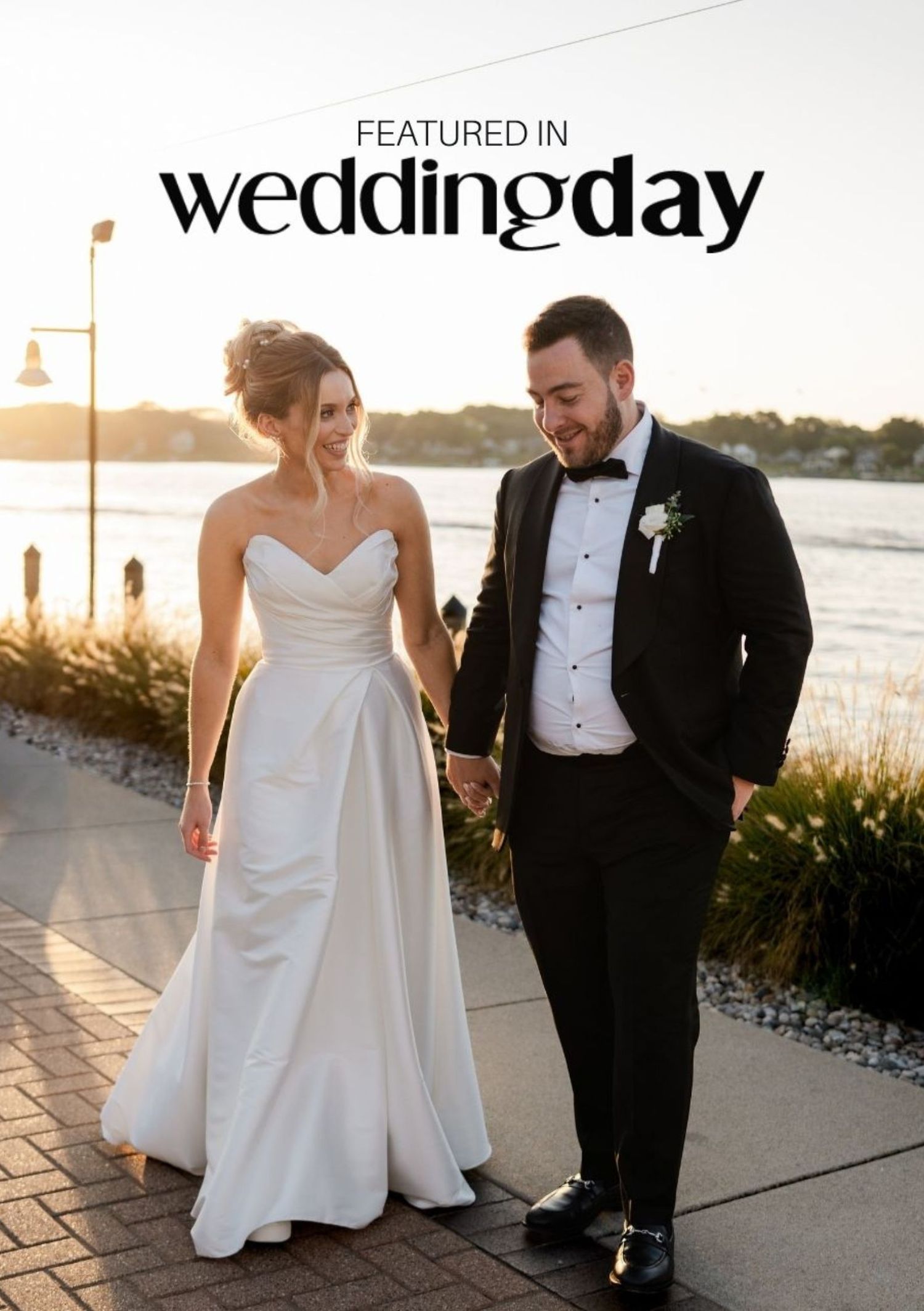 Bride and groom walking hand in hand outdoors near waterfront, featured in Wedding Day magazine.